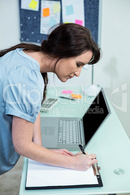 Pregnant woman writing on clipboard
