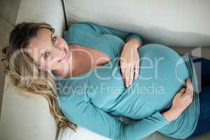 Pregnant woman touching her belly lying on the couch