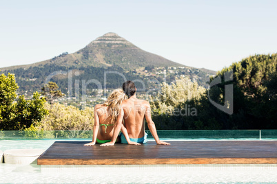 Rear view of couple sitting bu the pool
