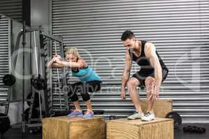 Couple doing box jumps in gym