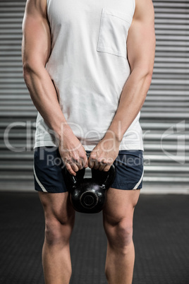 Midsection of fit man holding dumbbell