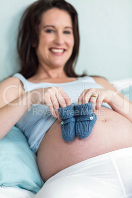 Pregnant woman with knitted slippers on her belly