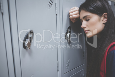 Sad student leaning on locker