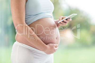 Pregnant woman touching her belly and texting