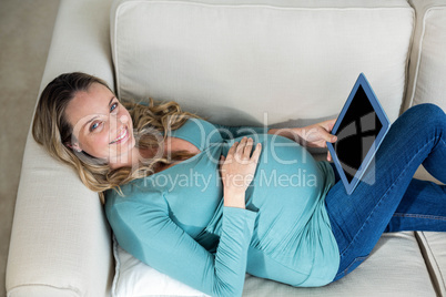 Pregnant woman using tablet lying on the couch