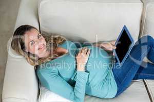 Pregnant woman using tablet lying on the couch