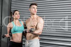 Fit couple lifting dumbbells and looking away