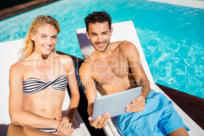 Couple using tablet on deckchairs