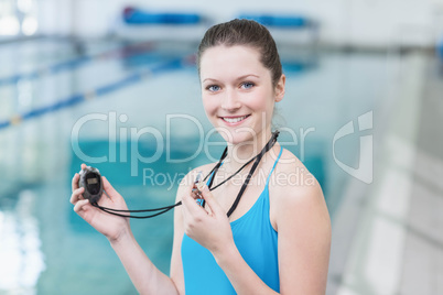 Pretty trainer blowing whistle and looking at stopwatch