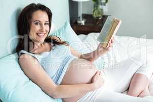 Pregnant woman on bed reading a book