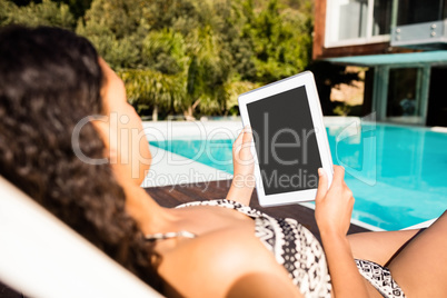 Fit brunette lying on deck chair and using tablet