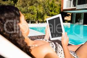 Fit brunette lying on deck chair and using tablet