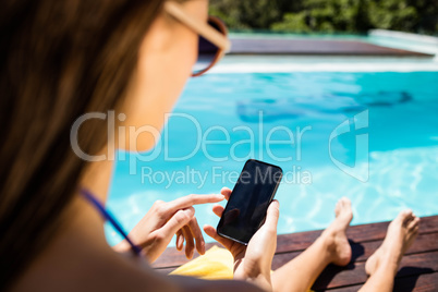 Brunette using smartphone poolside