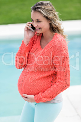 Pregnant woman touching her belly and making a phone call