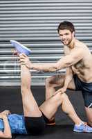 Male trainer assisting woman stretching