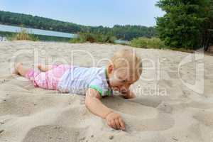 baby lays on the sand at the river