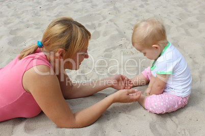 happy mother play about with her baby on the sand