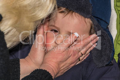 Frau cremt das Gesichtes  eines Kleinkindes ein.