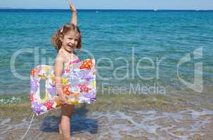 happy little girl standing in the sea with hand up