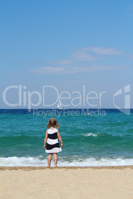 little girl looking boat at sea