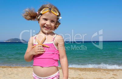 little girl with starfish posing on beach