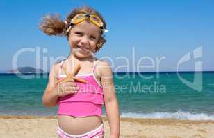 little girl with starfish posing on beach
