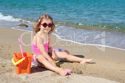 little girl with sunglasses playing on beach