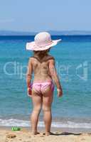 little girl with straw hat looking at sea