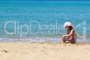 little girl with straw hat playing on the beach