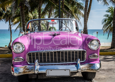 Pink Oldtimer parkt am Strand in Kuba