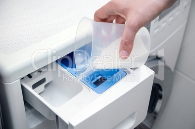 Woman hand pouring washing powder into the washing machine