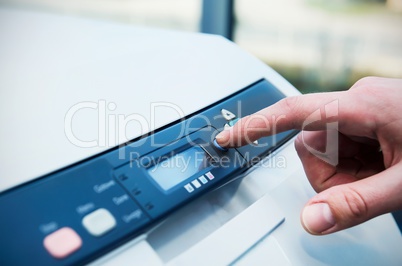 Finger on start button of laser printer