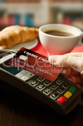 Man using payment terminal with NFC technology in cafeteria