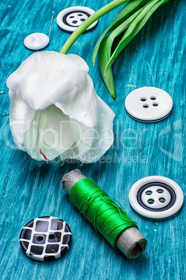 one white tulip and buttons with threads