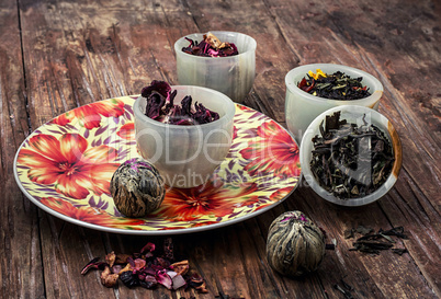 variety of dry tea leaves in jade stacks on wooden background