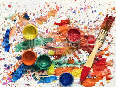 cans of paint and a brush on a sheet covered in paint