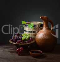 bowl with red wine pitcher with a barrel and grapes