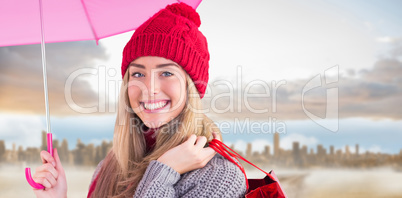 Composite image of festive blonde holding umbrella and bags