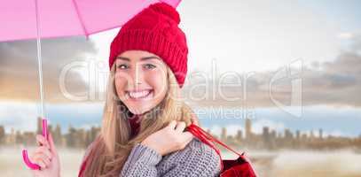 Composite image of festive blonde holding umbrella and bags