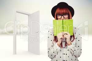 Composite image of hipster woman behind a green book