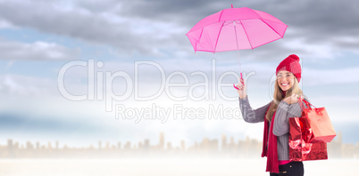 Composite image of festive blonde holding umbrella and bags