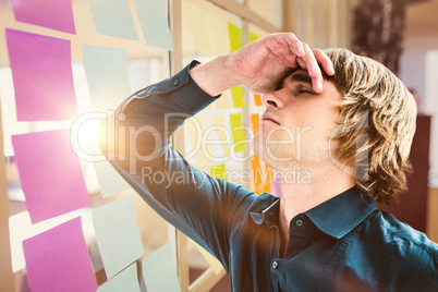 Composite image of troubled hipster businessman holding his head