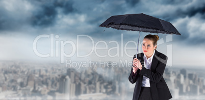 Composite image of businesswoman holding a black umbrella