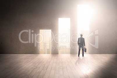 Composite image of rear view of businessman holding a briefcase