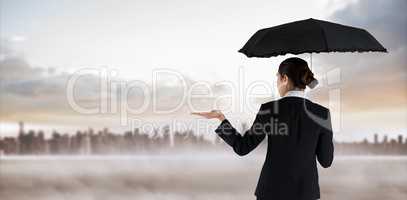 Composite image of young businesswoman holding umbrella