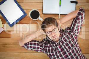 Composite image of hipster wearing eye glasses lying on hardwood