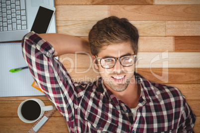 Composite image of hipster smiling while lying by laptop on hard