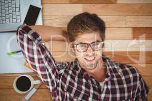 Composite image of hipster smiling while lying by laptop on hard