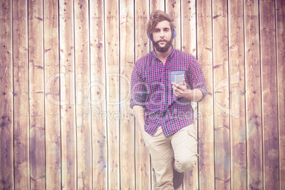 Composite image of hipster holding mobile phone listening music