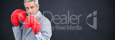 Composite image of tough businessman with boxing gloves